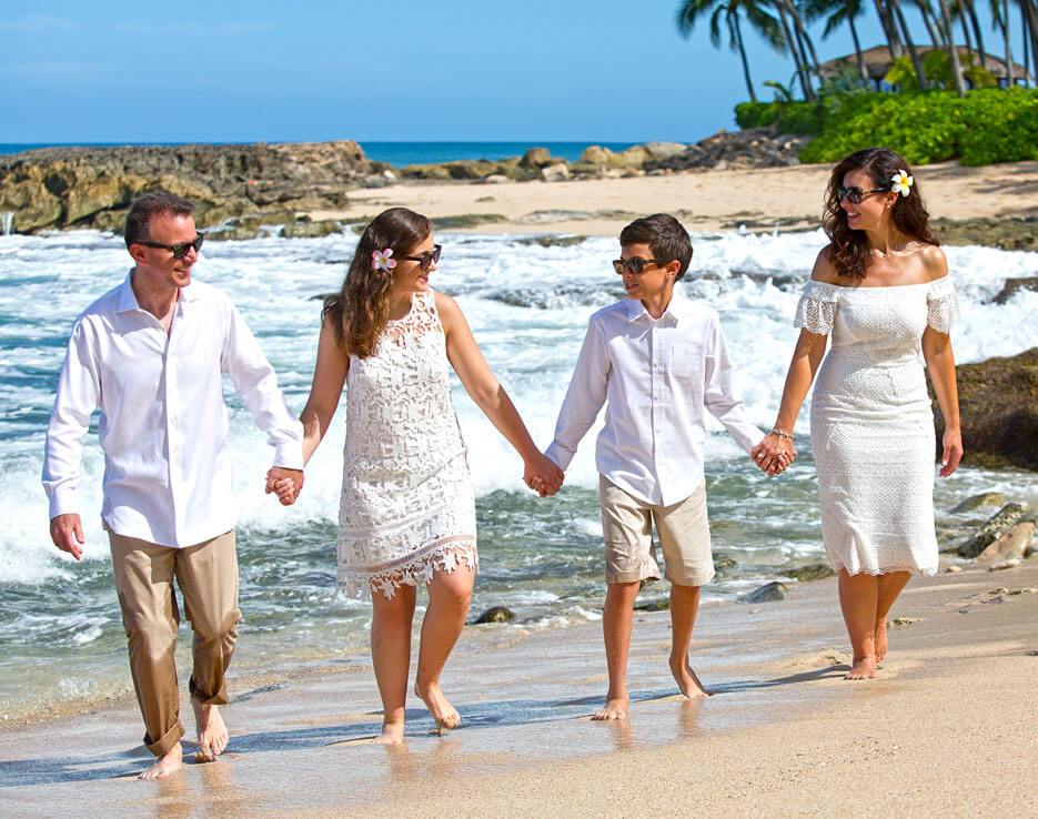 Beach family lifestyle photography - Family of four holding hands walking on the sand at Secret Beach, Koolina.