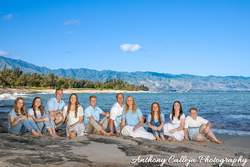 Family of ten sitting on the rocks at Papailoa Beach, North Shore, Oahu