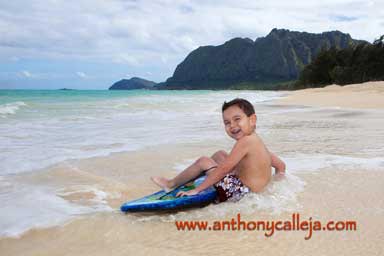 little boy having fun boogie bording on the beach at Waimanalo Beach Oahu Hawaii