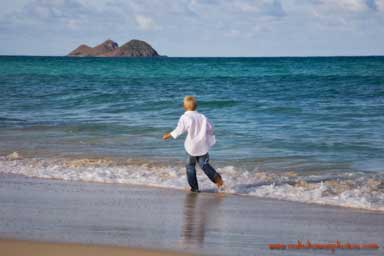 young boy running on the white sand beach of Waimanalo Beach Oahu Hawaii