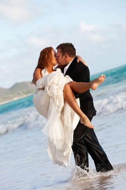 Groom carrying bride in the water kissing