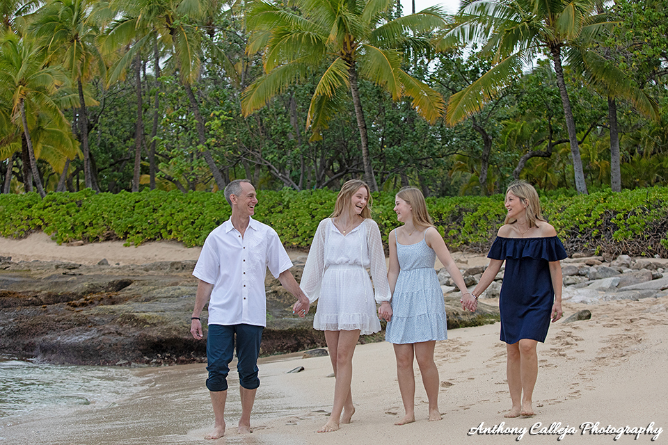 fun beach family photo session - portrait of a family of four laughing, holding hands, walking on the sands of Secret Beach, Koolina